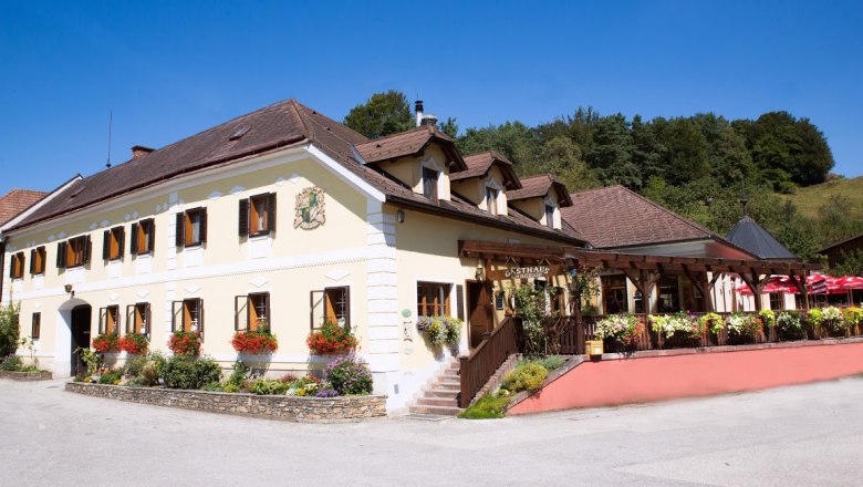 Traditionelles Gasthaus gelber Fassade, vielen Fenstern und Terasse.