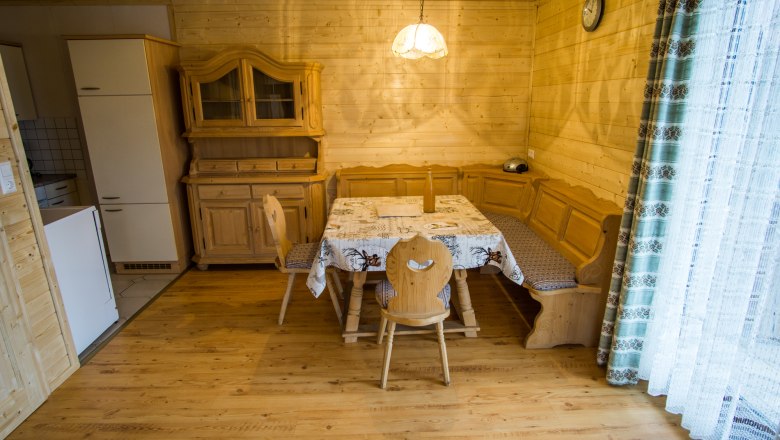 Essbereich in einem rustikalen Ferienhaus mit Holzm&ouml;beln und Eckbank.