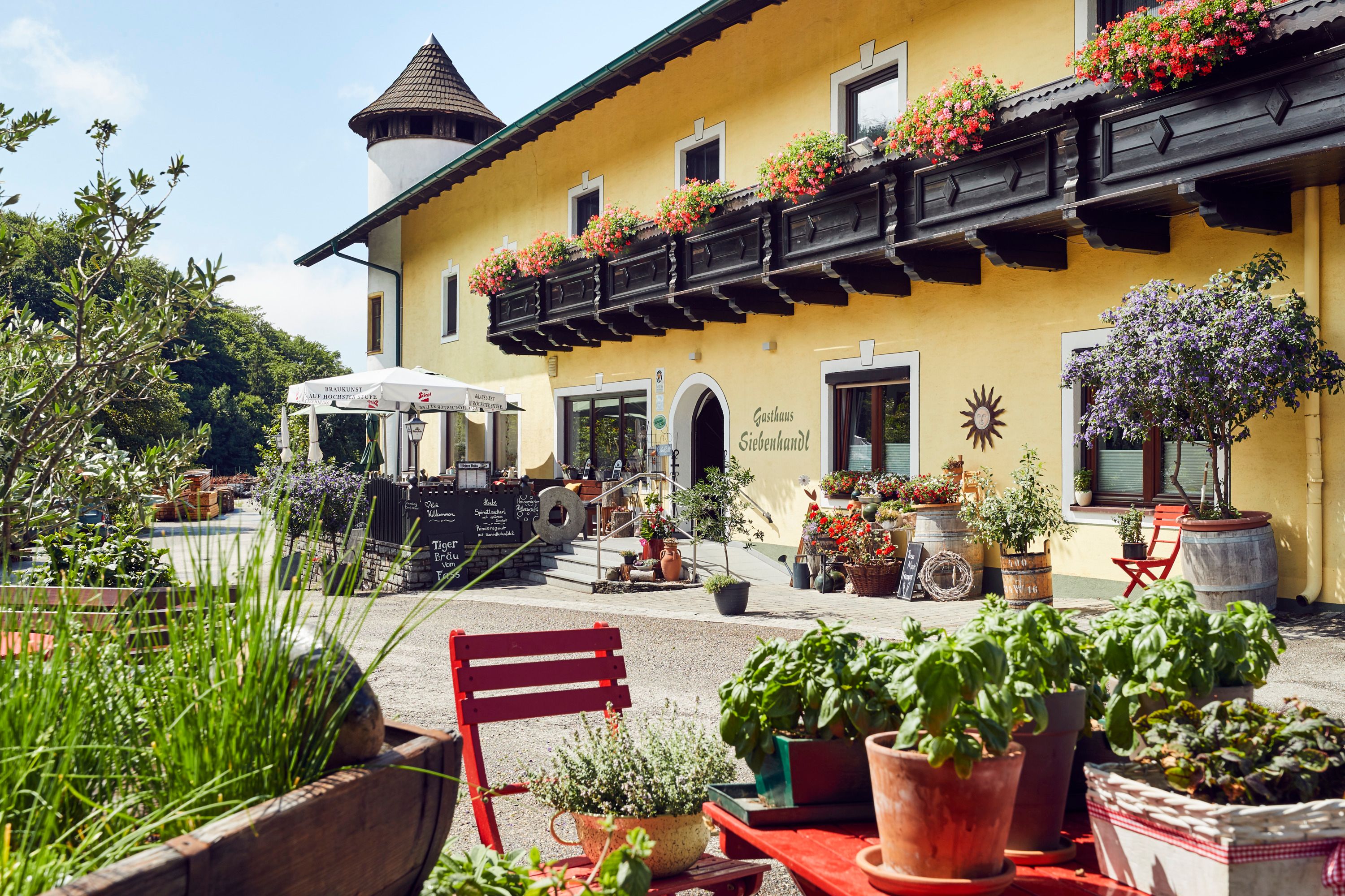 Gemütliches Gasthaus mit Blumenschmuck und Terrasse, ländliche Atmosphäre.