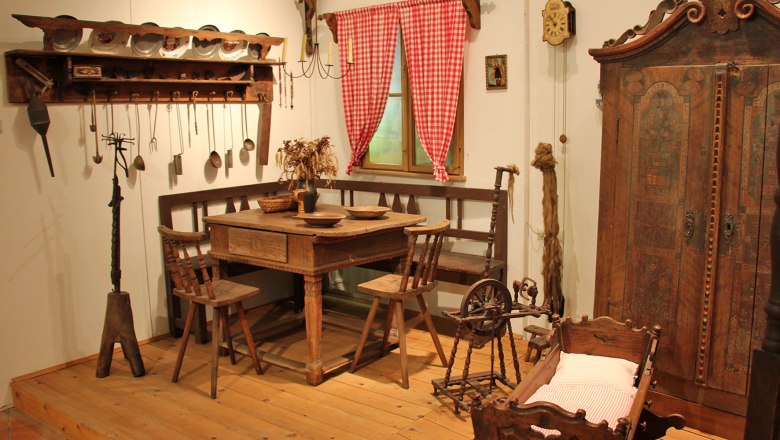 Historische Bauernstube mit Holzm&ouml;beln, Spinnrad und Wiege.