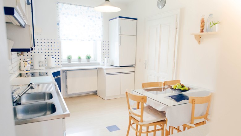 Helle K&uuml;che mit Esstisch, St&uuml;hlen und modernen Ger&auml;ten.