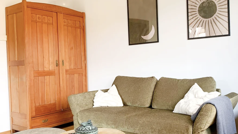 green sofa in room with wooden floor and wardrobe