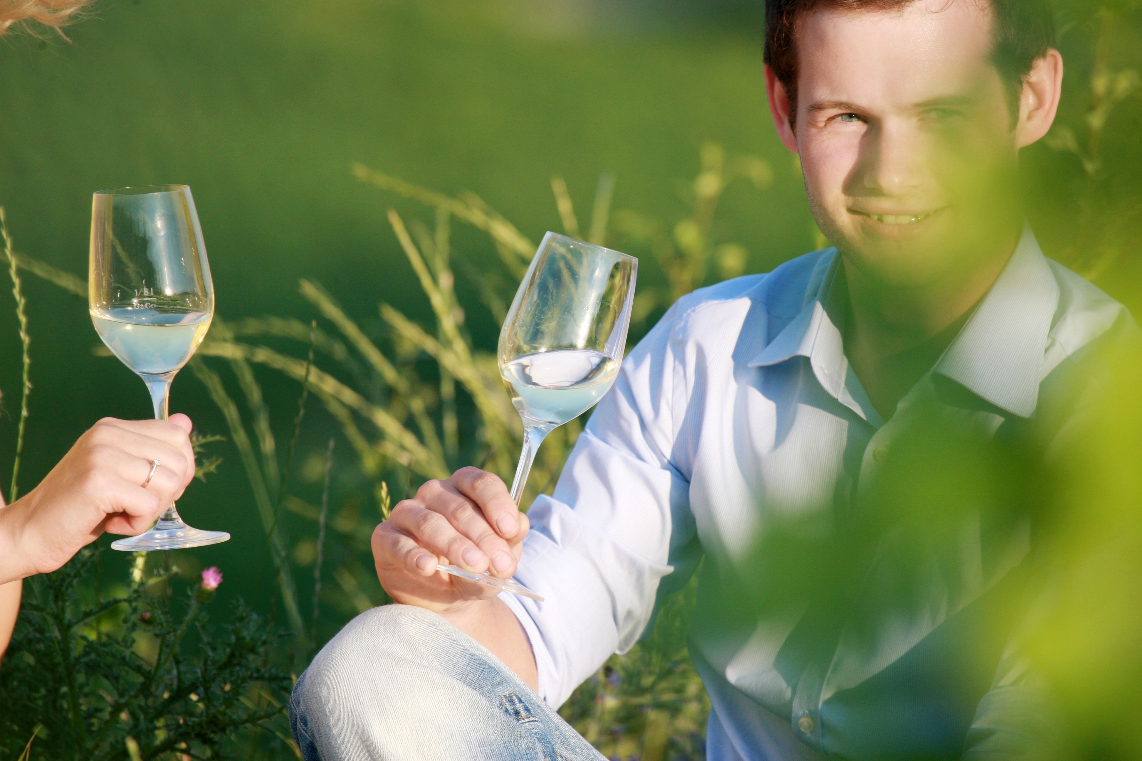 Zwei Personen stoßen mit Weingläsern im Freien an.
