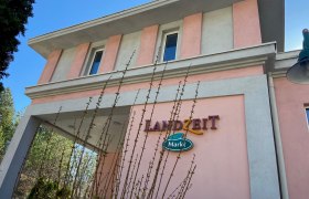 Gebäude mit rosa und grauer Fassade, Schriftzug 'Landzeit Markt'.