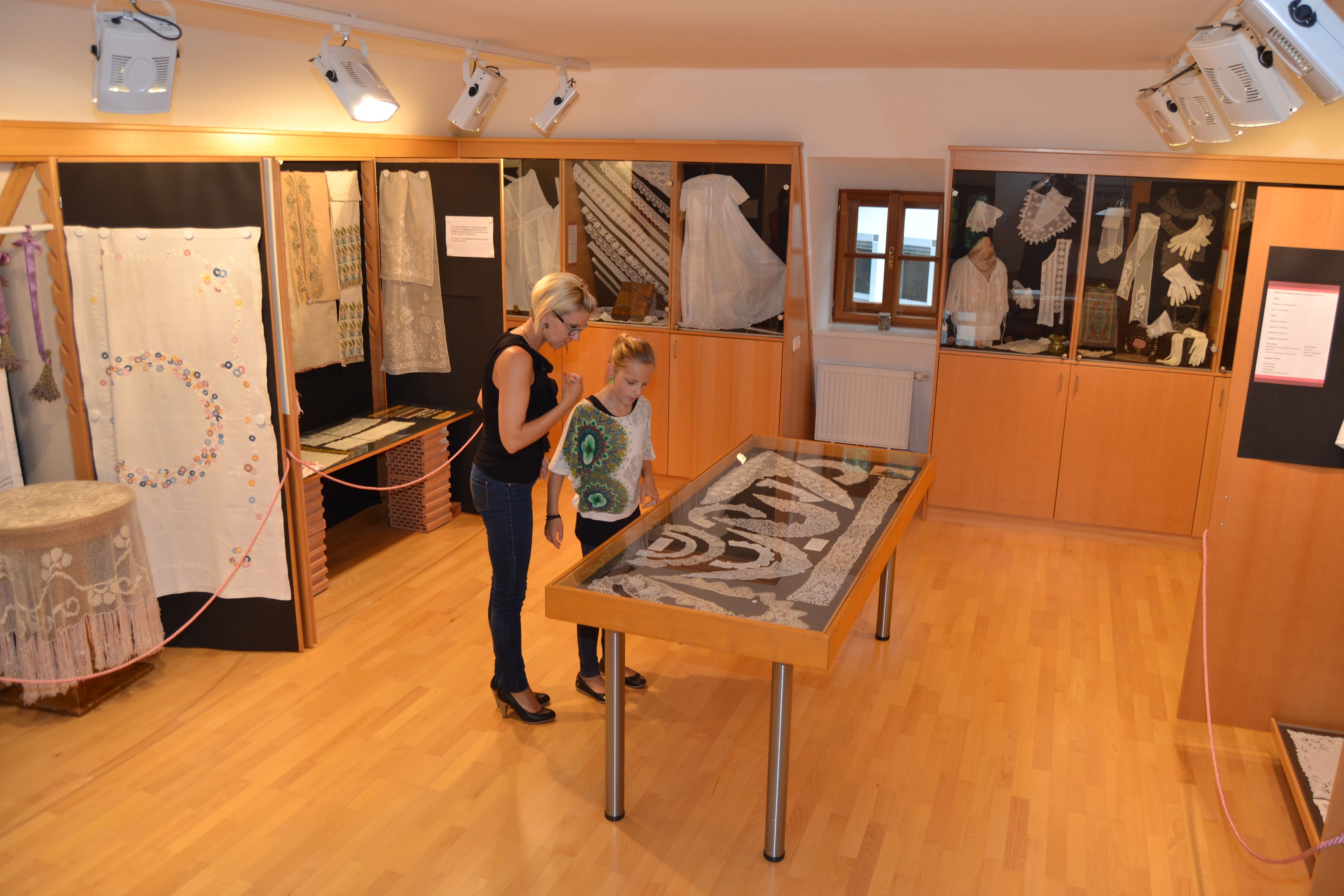 Zwei Personen betrachten Exponate in einem Handarbeitsmuseum.