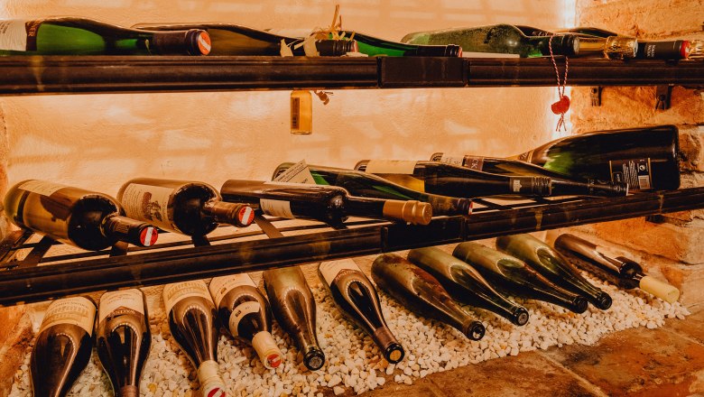 Weinflaschen in einem Regal auf weißen Steinen.