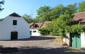 Traditionelle Weinkeller in einer l&auml;ndlichen Umgebung mit B&auml;umen und blauem Himmel.