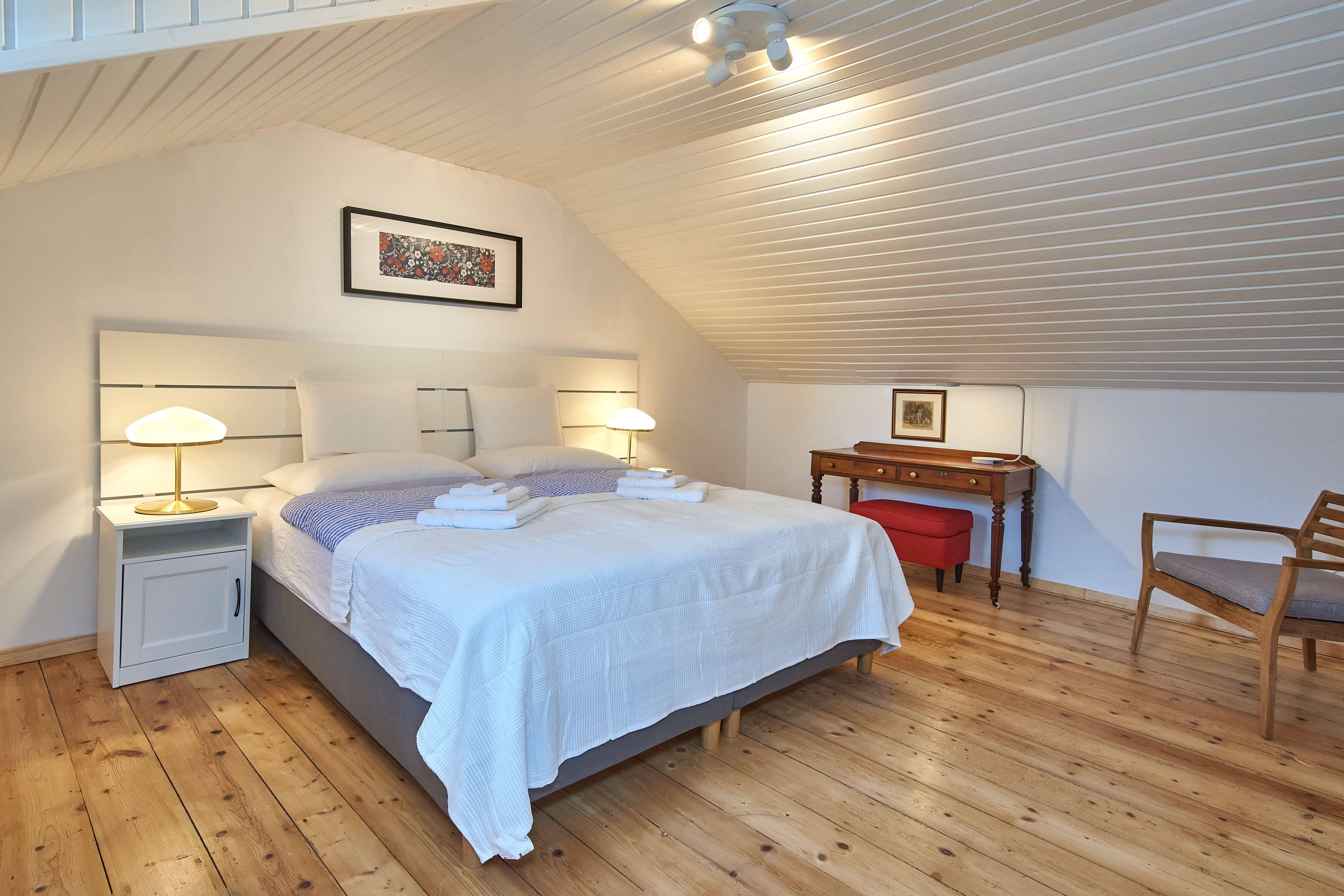 Gemütliches Schlafzimmer mit Doppelbett, Holzboden und Dachschräge.