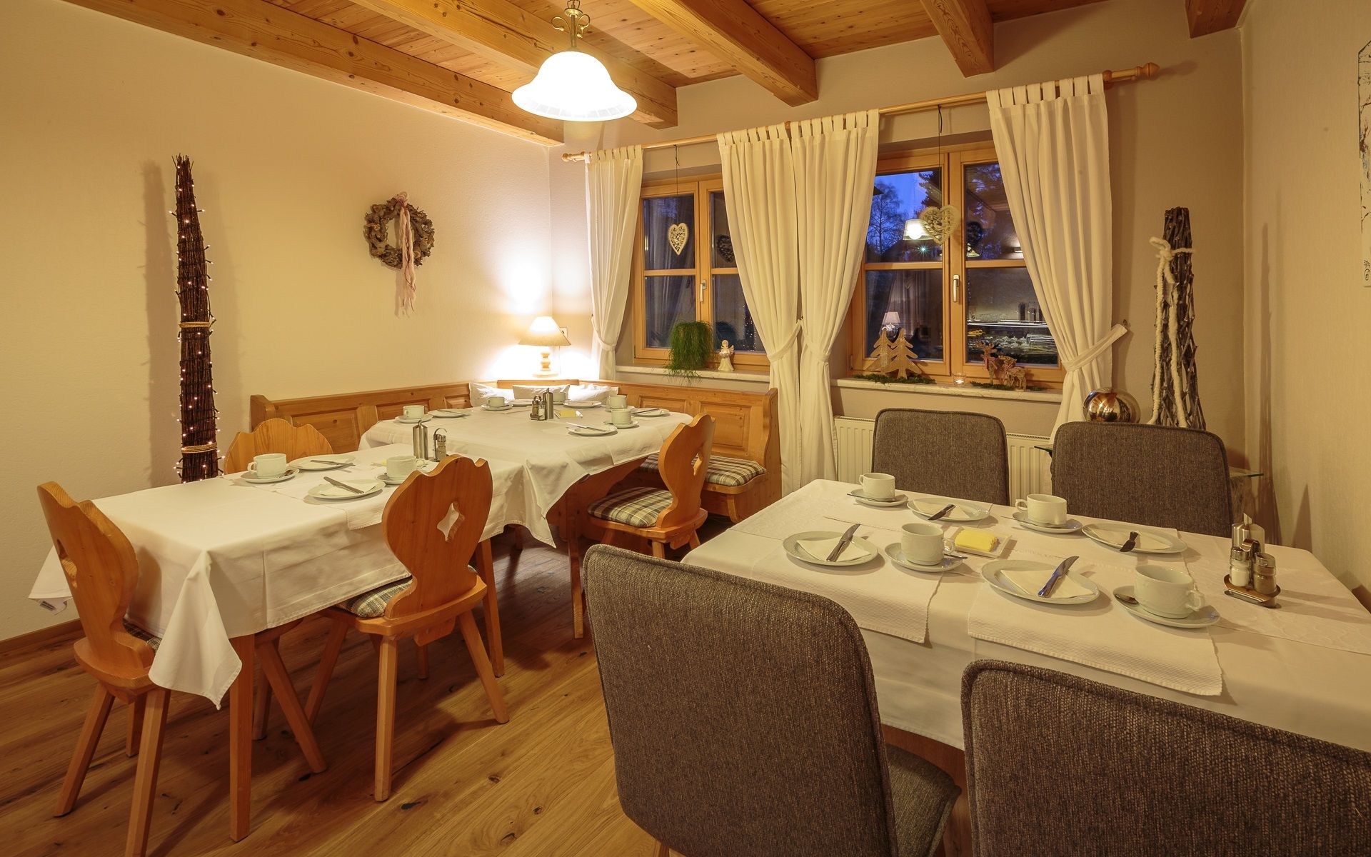 Gemütlicher Frühstücksraum mit gedeckten Tischen, Holzmöbeln und Dekorationen.