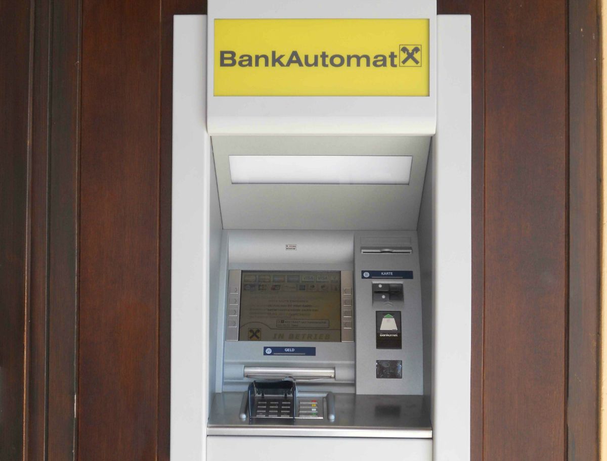 Ein Bankautomat mit gelbem Schild und Raiffeisen-Logo.