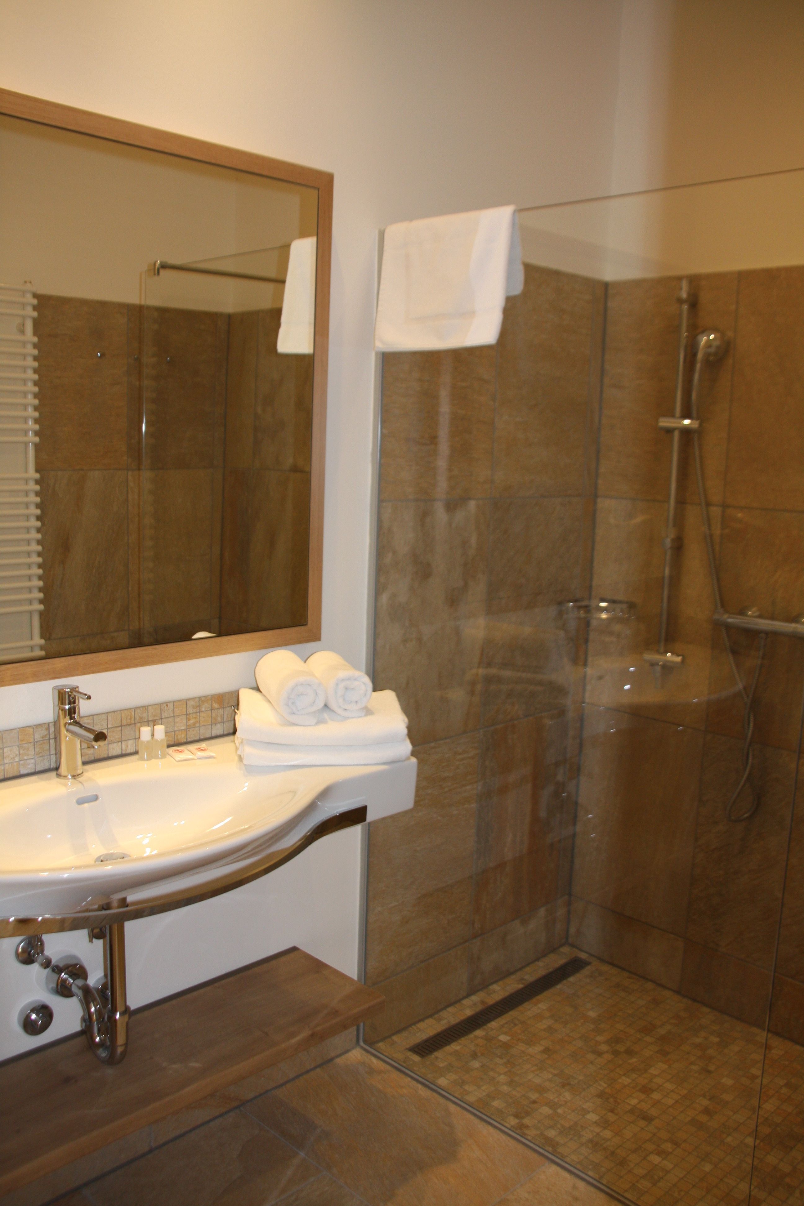 Modernes Badezimmer mit Waschbecken, Spiegel und Dusche.
