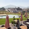Terrasse mit Pool, Sonnenschirmen und Blick auf Weinberge und Hügel.