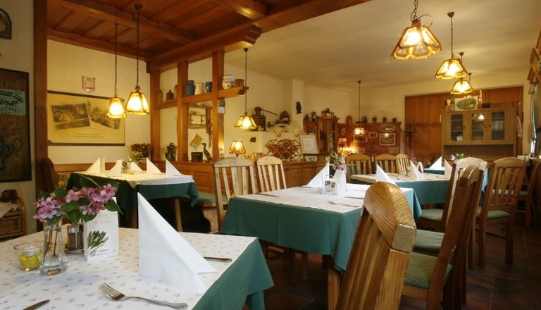 Innenansicht eines gem&uuml;tlichen Wirtshauses mit Holzm&ouml;beln und gedeckten Tischen.