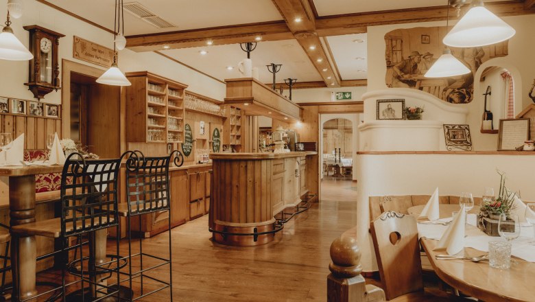 Gem&uuml;tliches Restaurant mit Holzm&ouml;beln, Bar und gedeckten Tischen.