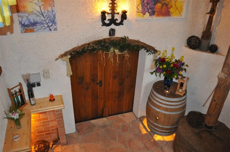 Rustikale Weinkellerdekoration mit Holztür, Blumen und Weinfass.