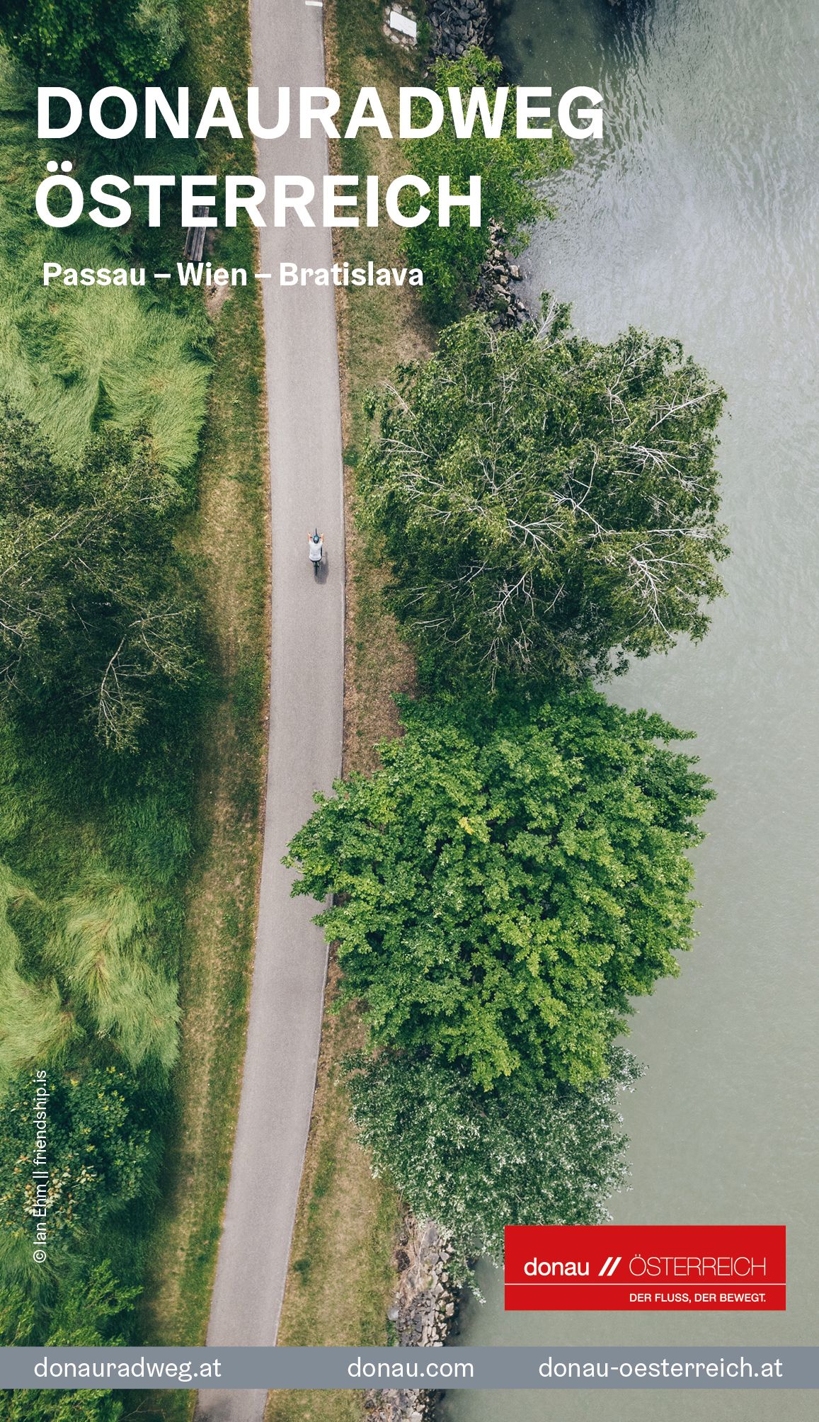 Coverbild: Blick aus der Vogelperspektive auf Person, die am Donauradweg entlang der Donau mit dem Rad fährt. 