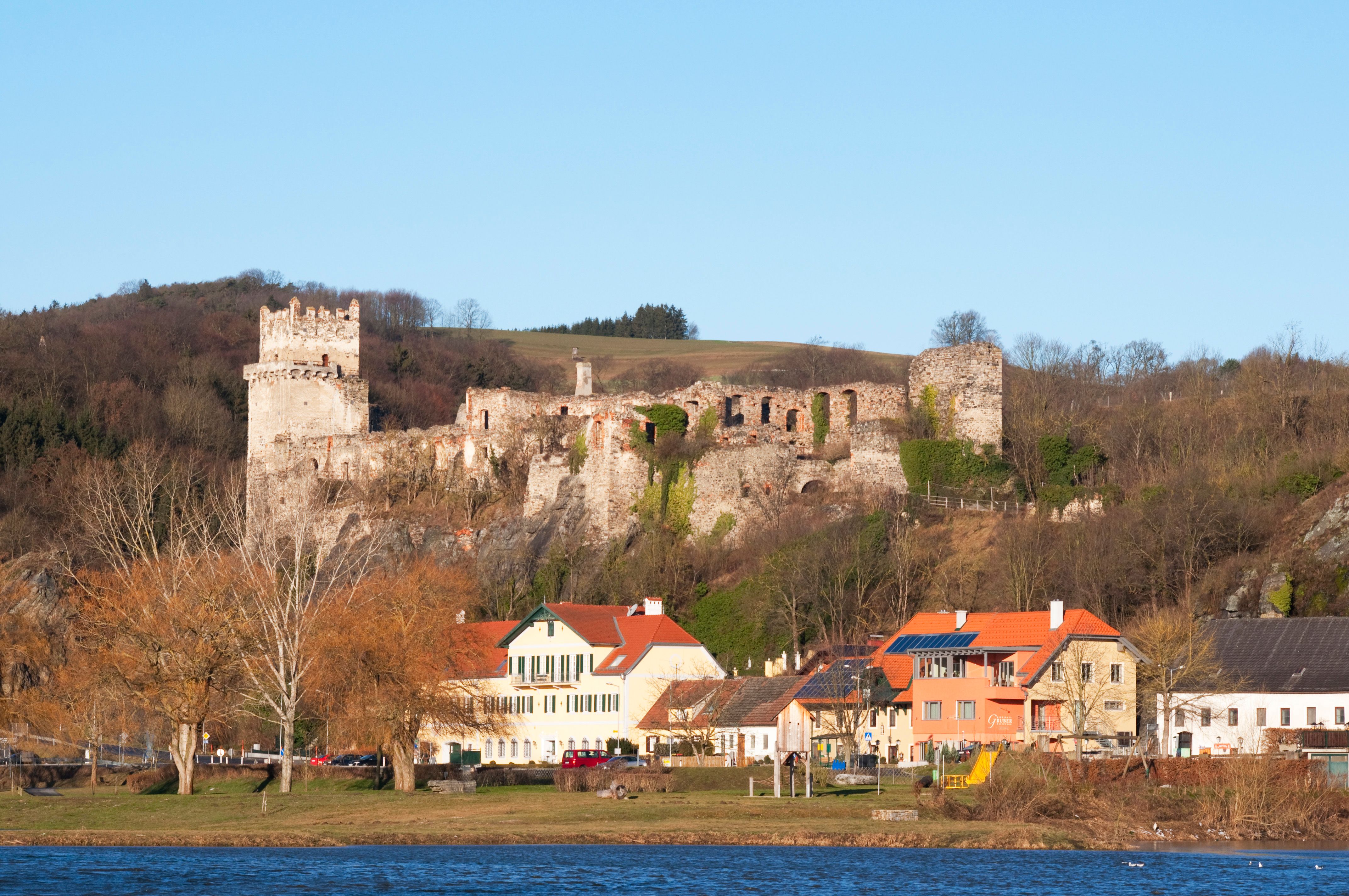 Ruine Weitenegg über einem Dorf am Flussufer.