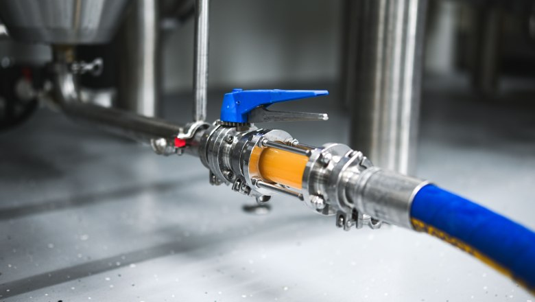 Nahaufnahme eines Brauereischlauchs mit Ventil und durchflie&szlig;ender Fl&uuml;ssigkeit.