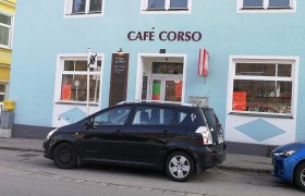 Außenansicht des Café Corso mit geparktem Auto davor.
