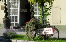 Eingang zu einer Pension mit einem dekorierten Fahrrad und einem Schild für Privatzimmer.