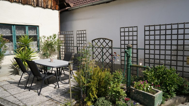 Ein gemütlicher Innenhof mit Tisch, Stühlen und Pflanzen.