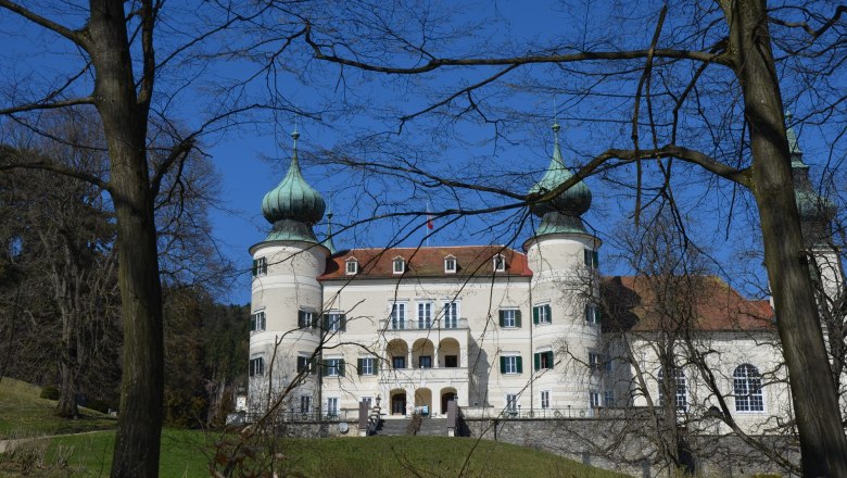 Schloss Artstetten mit zwei markanten Türmen und blauer Himmel im Hintergrund.