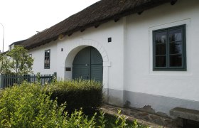 Das Geburtshaus von Joseph Haydn in Rohrau, ein wei&szlig;es Geb&auml;ude mit Strohdach und gr&uuml;ner T&uuml;r.
