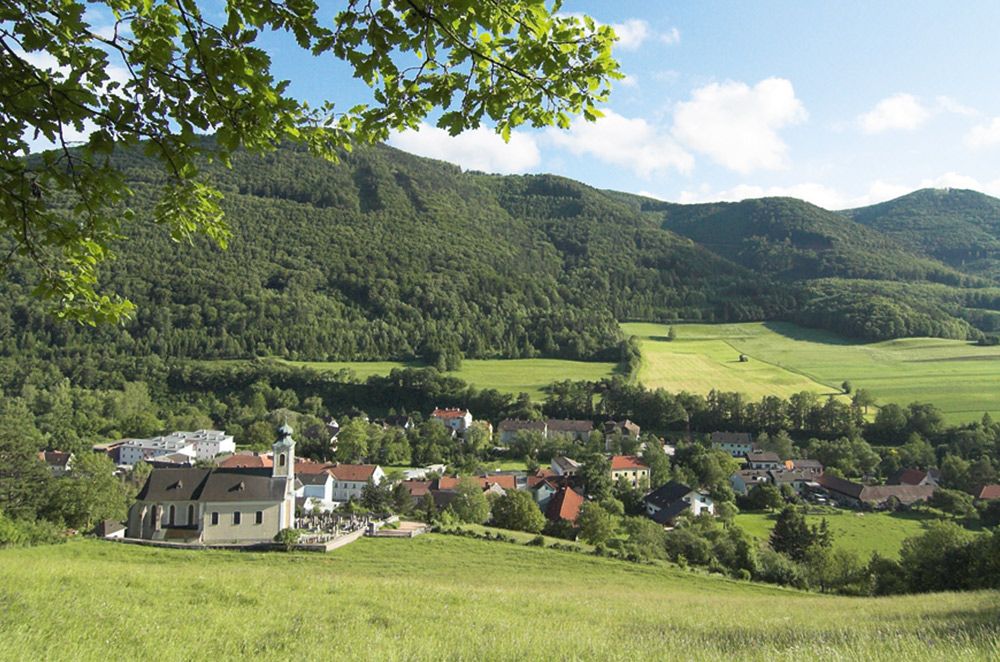 Blick auf Altenmarkt mit Kirche und grüner Landschaft im Hintergrund.