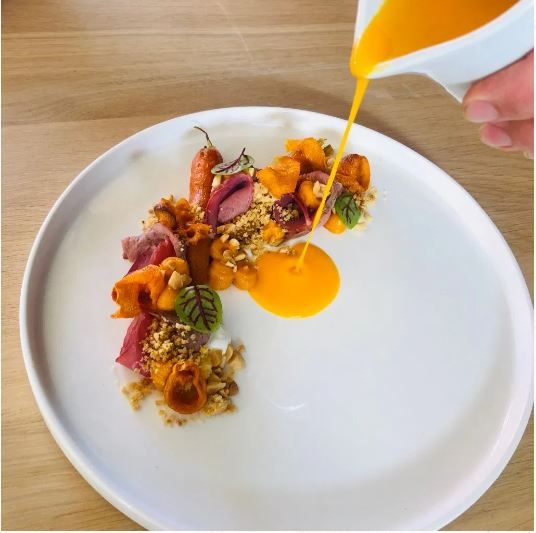 Detailaufnahme eines angerichteten Gerichts mit frischen Zutaten; hochwertige Präsentation in modernem Restaurantambiente.