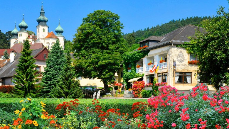 Ein malerisches Hotel mit bunten Blumen im Vordergrund und einem Schloss im Hintergrund.