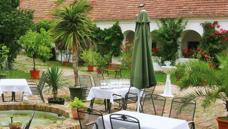 Ein idyllischer Innenhof mit Tischen, Stühlen, Pflanzen und einem Brunnen.