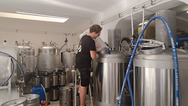 Person arbeitet an einem Braukessel in einer Brauerei.