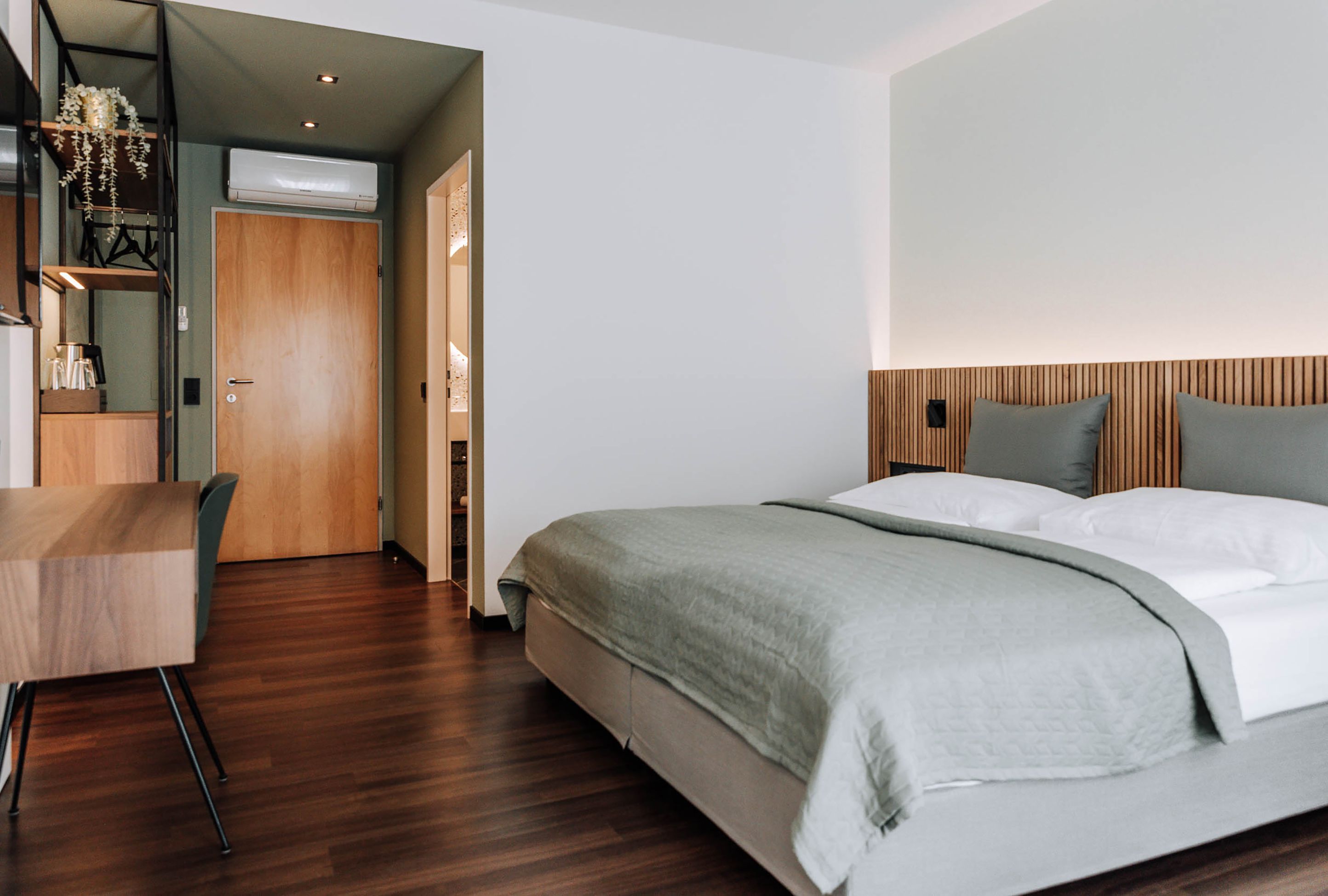 Modernes Hotelzimmer mit Doppelbett, Holzboden und Schreibtisch.