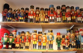 Eine Sammlung von bunten Nussknackerfiguren auf zwei Holzregalen.