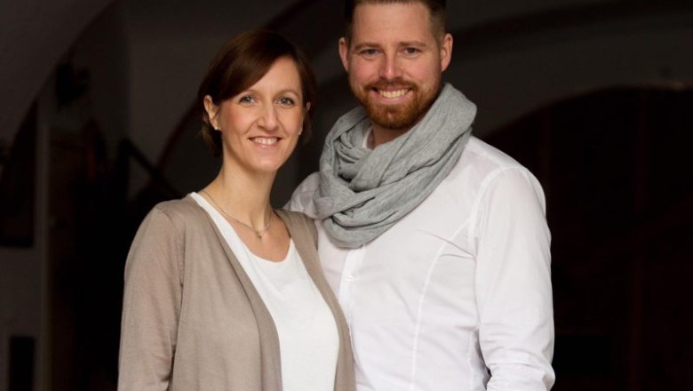 Ein l&auml;chelndes Paar steht nebeneinander, der Mann tr&auml;gt einen Schal.