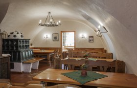 Innenansicht eines traditionellen Heurigenlokals mit Holzm&ouml;beln und Kachelofen.