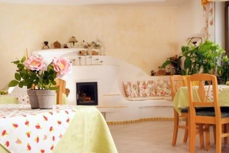 Frühstücksraum, © Familie Grün Gemütlicher Frühstücksraum mit Holzmöbeln, Pflanzen und einem kleinen Kamin.