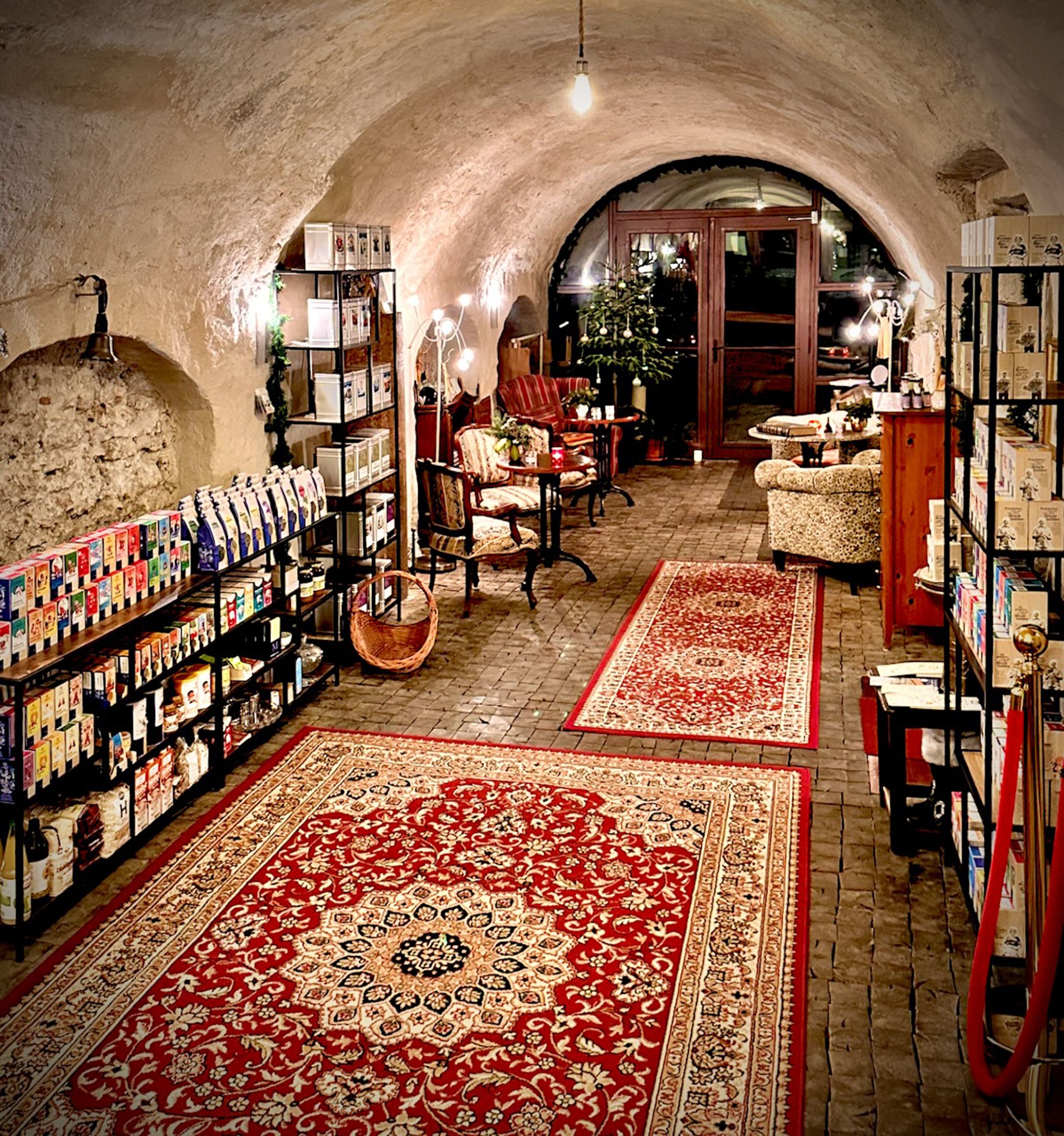 Gemütlicher Raum mit roten Teppichen, Regalen voller Produkte und Sitzgelegenheiten im Teesalon.