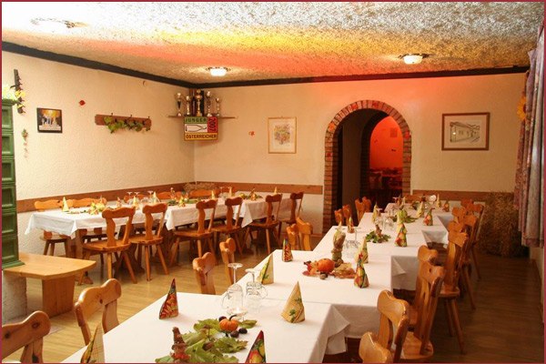 Gemütlicher Gastraum mit Holzmöbeln und gedeckten Tischen.