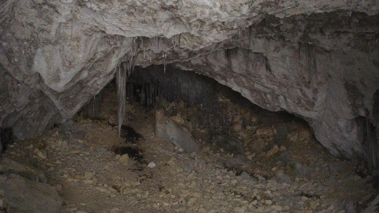 Innenansicht einer trockenen H&ouml;hle mit Stalaktiten und steinigem Boden.
