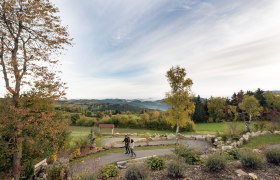 In der sanften H&uuml;gellandschaft entfaltet sich ein malerisches Panorama, das die Seele ber&uuml;hrt. Die bunten Bl&auml;tter der B&auml;ume k&uuml;ndigen den Herbst an und laden zu einem entspannenden Spaziergang ein. Hier, wo die Natur in voller Pracht erstrahlt, findet man den perfekten Ort, um die Ruhe und Sch&ouml;nheit der Umgebung zu genie&szlig;en.