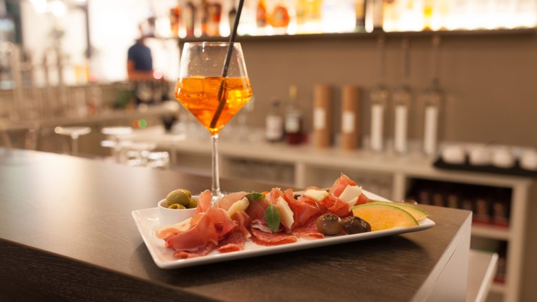 Kleiner Imbis und Getränk im Weinglas stehen an der Hotelbar