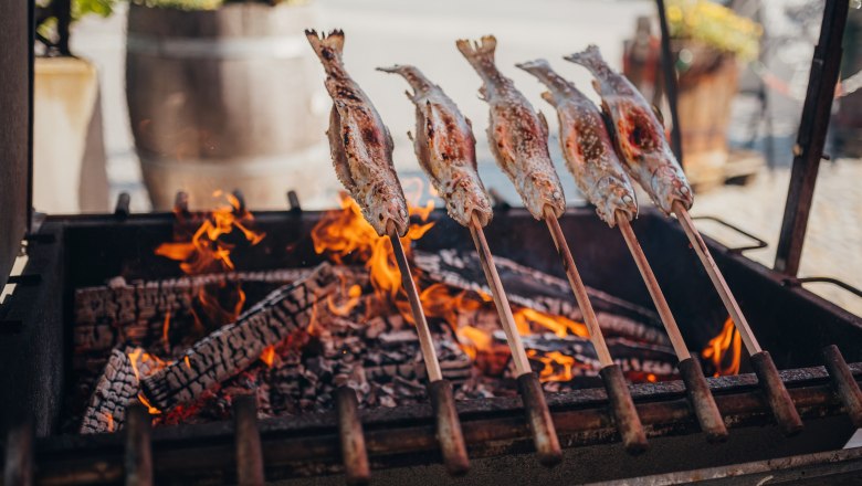 Steckerlfisch über offenem Feuer gegrillt, traditionelle Zubereitung.