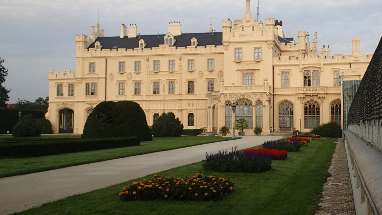 Schloss Lednice mit gepflegtem Garten und Blumenbeeten im Vordergrund.