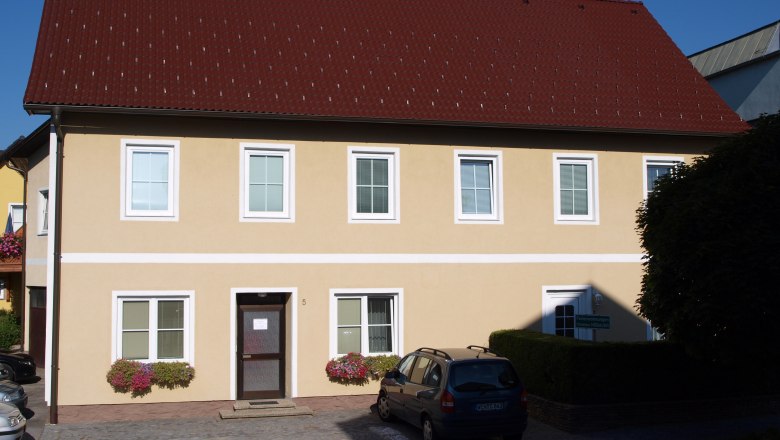 Gelbes zweist&ouml;ckiges Haus mit rotem Dach und mehreren Fenstern.