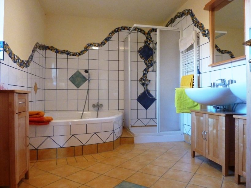 Ein Badezimmer mit Eckbadewanne, Dusche, Waschbecken und Fliesen in Blau und Weiß.