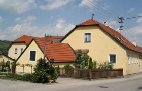 Gelbes Haus mit rotem Dach in ländlicher Umgebung.