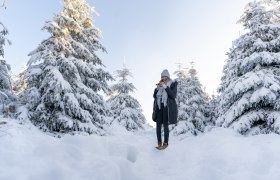 Frau steht im verschneiten Wald