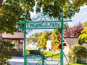 Gr&uuml;nes Tor mit Aufschrift "Eingang in den Park", im Hintergrund ist der Pavillon und die Rax zu sehen.