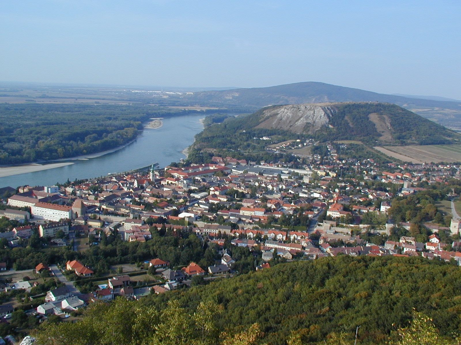 Panoramablick auf eine Stadt mit Fluss und Hügeln im Hintergrund.